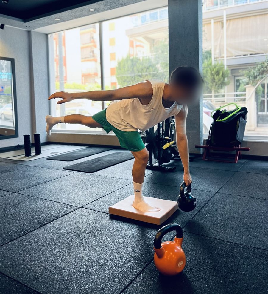 Stüdyoda denge pedinde tek bacak deadlift çalışan sporcu