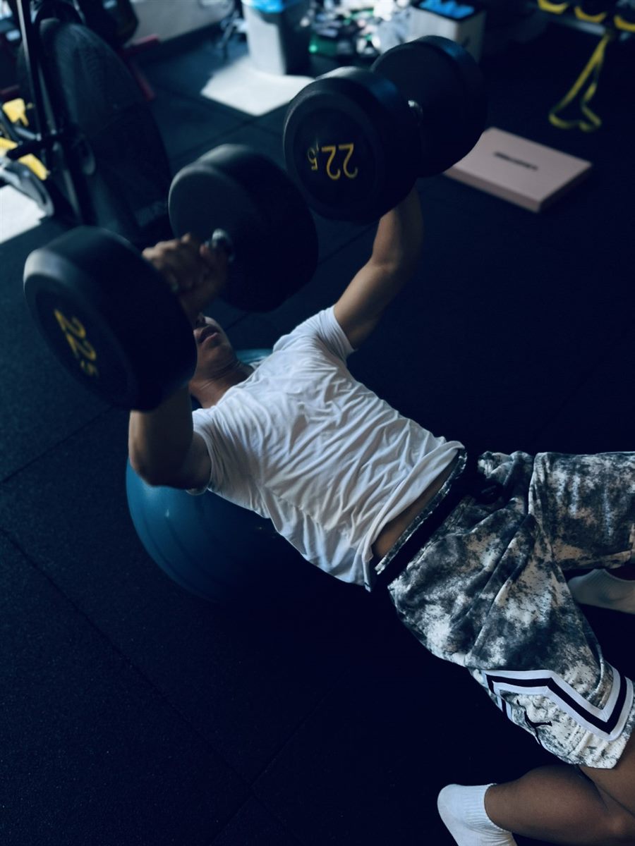 Pilates topu üzerinde dambıl pres çalışan sporcu